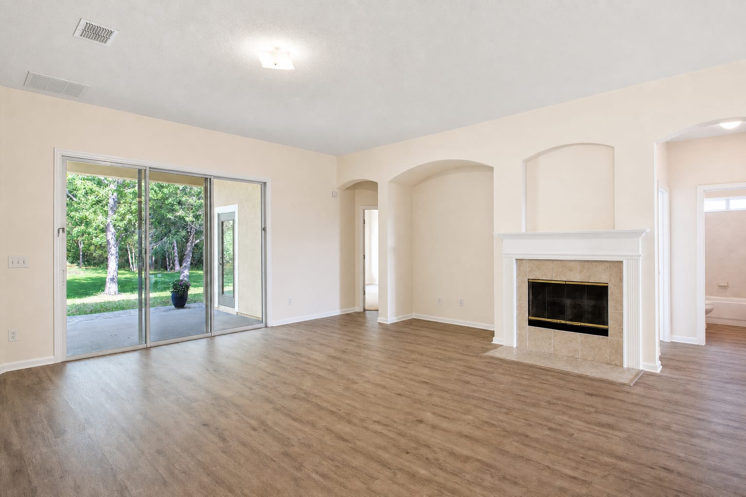 Same living room with photo enhancement only: clean exposure, accurate color, restored window view, but still empty.